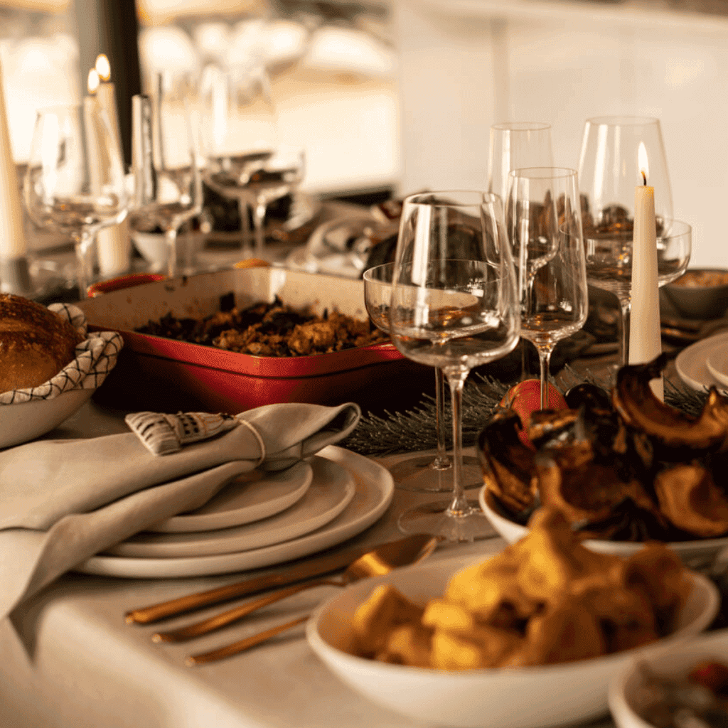 Elegant holiday dinner table with wine glasses, candles, and festive dishes for Christmas celebration. Shop Fable Home.