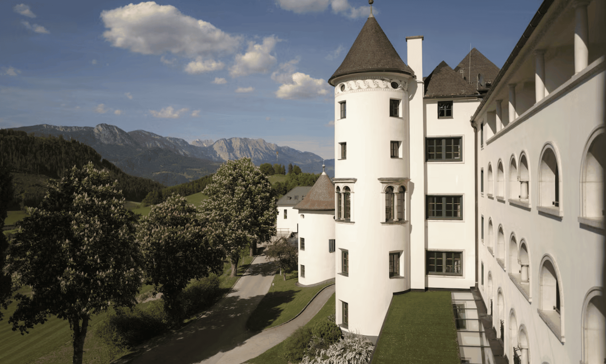 Elegant castle hotel with turrets and scenic mountain views in the background.